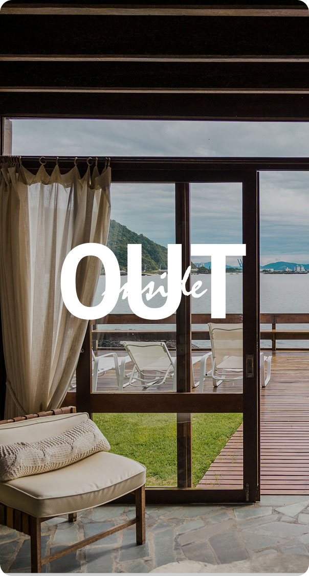 interior room with chair and curtains opening to ocean view terrace with lounge chairs