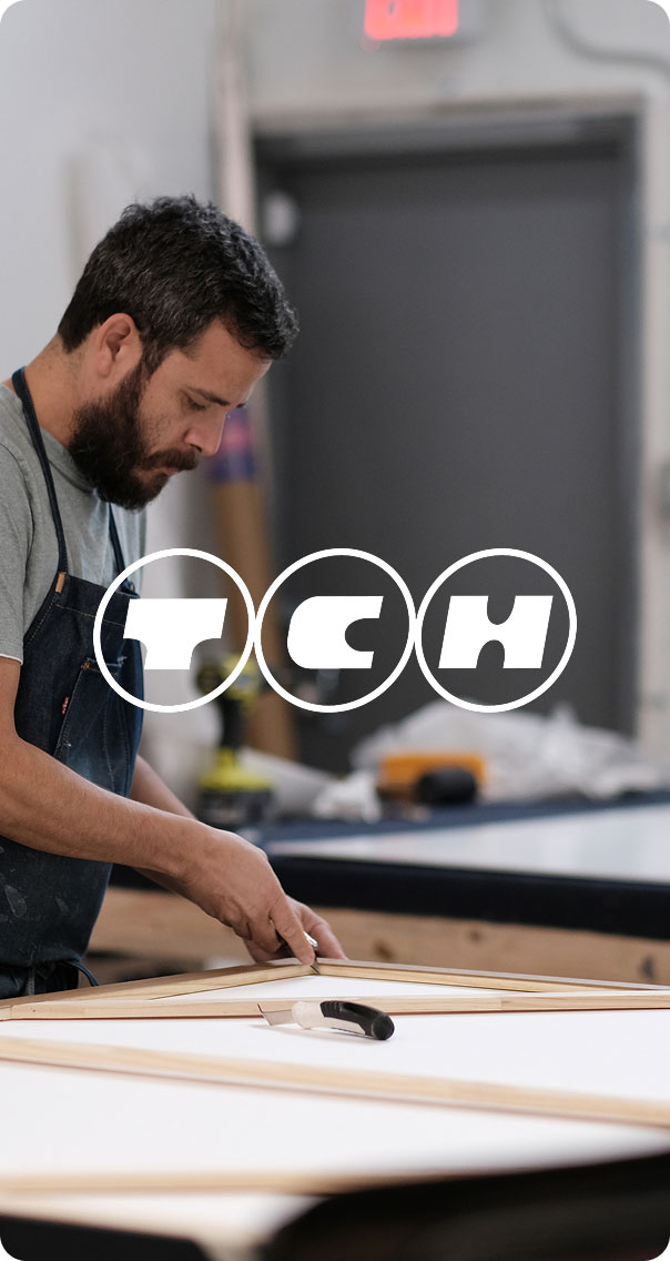 technician assembling wooden frame for print or artwork in workshop
