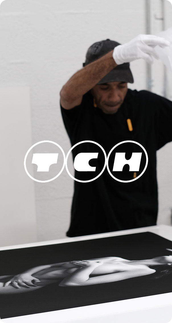 man wearing gloves working on black and white print in studio, creative photography production process
